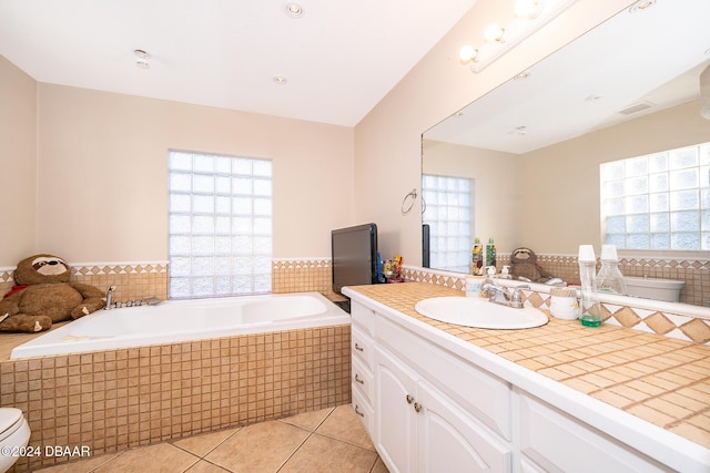 bathroom featuring toilet, vanity, tile patterned floors, and tiled tub