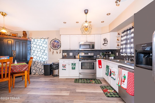 kitchen featuring white cabinetry, sink, decorative light fixtures, and appliances with stainless steel finishes