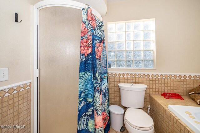 bathroom featuring toilet, tile walls, and a healthy amount of sunlight