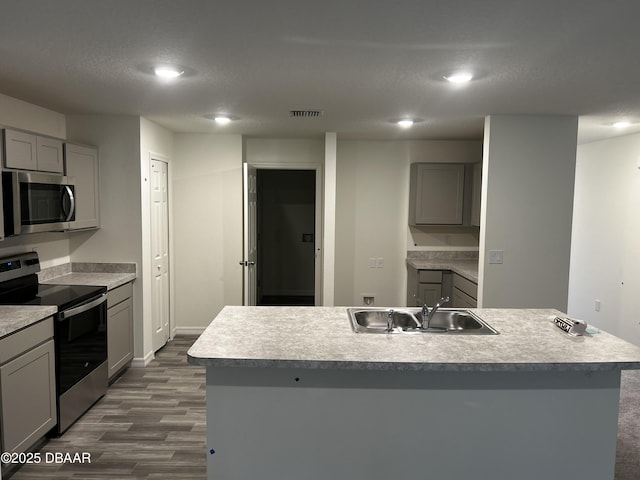 31 Palm Leaf Ln, Palm Coast, FL 32164 - kitchen with gray cabinets, appliances with stainless steel finishes, a kitchen island with sink, dark wood finished floors, and recessed lighting