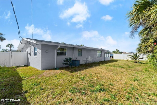 rear view of property with cooling unit and a lawn