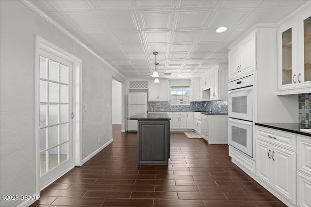 kitchen featuring white cabinetry, backsplash, white appliances, and a kitchen island