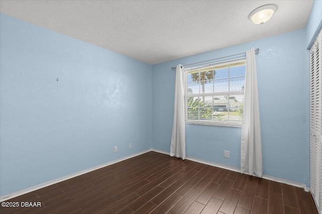 spare room featuring dark hardwood / wood-style floors and a textured ceiling