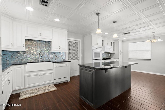 kitchen featuring sink, white appliances, white cabinetry, a center island, and decorative light fixtures