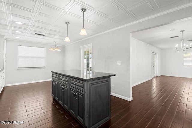 kitchen with crown molding, decorative light fixtures, a center island, and a chandelier