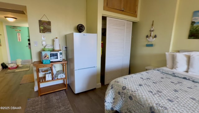 bedroom featuring dark wood-type flooring, a closet, and white fridge