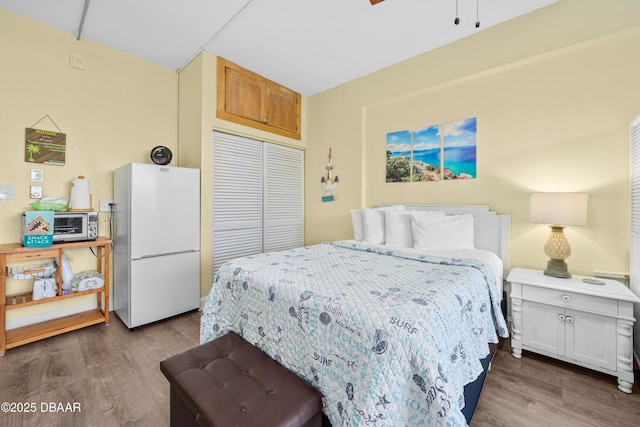 bedroom featuring wood-type flooring, a closet, and white fridge