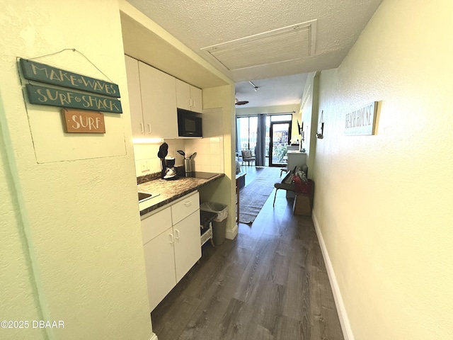 hallway with dark wood-type flooring and a textured ceiling