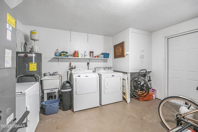 clothes washing area with water heater, separate washer and dryer, and sink