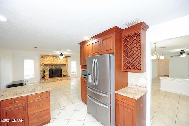 kitchen featuring stainless steel appliances, a fireplace, light tile patterned floors, and ceiling fan with notable chandelier