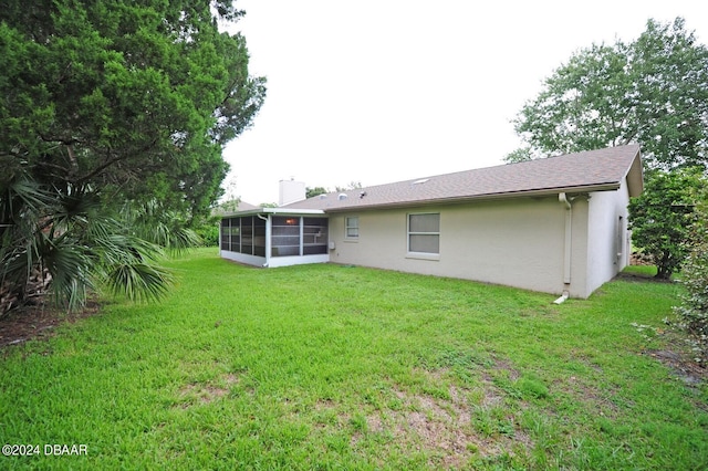 1889 Seclusion Dr, Port Orange, FL 32128 - rear view of property featuring a sunroom, stucco siding, a yard, and a chimney