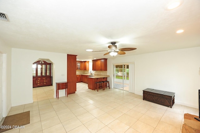 kitchen featuring kitchen peninsula, a breakfast bar area, ceiling fan, and light tile patterned floors