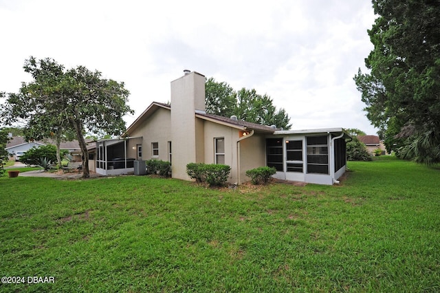1889 Seclusion Dr, Port Orange, FL 32128 - back of house with a sunroom, a chimney, a yard, stucco siding, and central air condition unit
