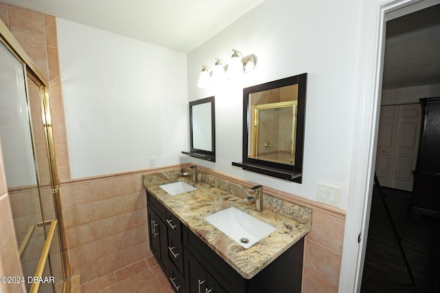 bathroom with vanity, a shower with shower door, tile patterned floors, and tile walls