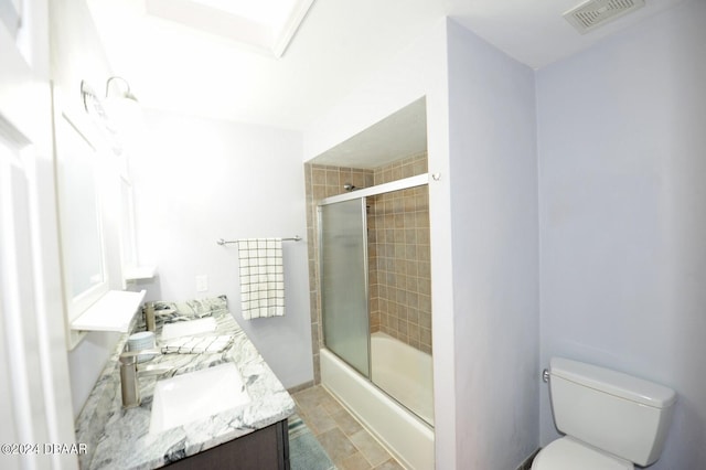 full bathroom featuring bath / shower combo with glass door, vanity, and toilet