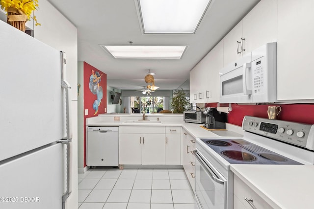 kitchen featuring a sink, white appliances, light tile patterned flooring, light countertops, and white cabinets
