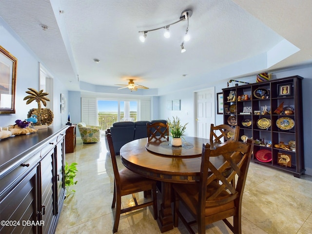 dining space with a textured ceiling, light tile patterned floors, and ceiling fan