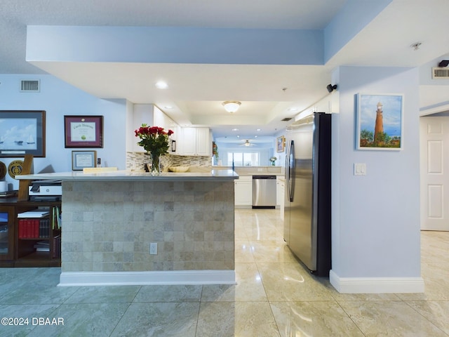 kitchen with stainless steel appliances, white cabinets, a raised ceiling, and kitchen peninsula