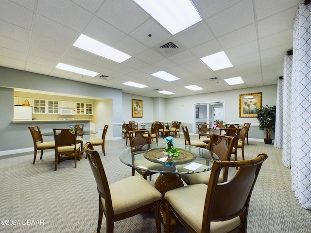 carpeted dining space with a drop ceiling