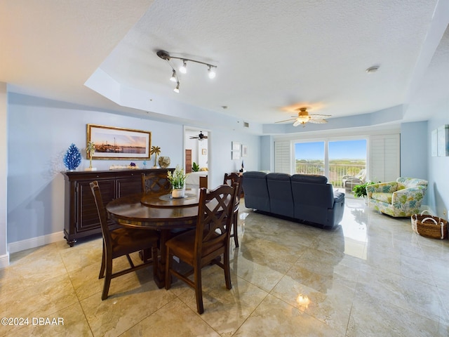 dining room with ceiling fan, a textured ceiling, and a tray ceiling