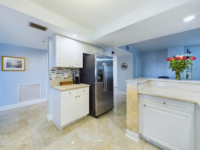 kitchen with white cabinets, stainless steel fridge with ice dispenser, backsplash, and kitchen peninsula