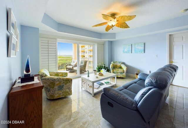 living room with ceiling fan and a textured ceiling