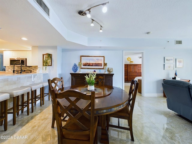 tiled dining space with a textured ceiling