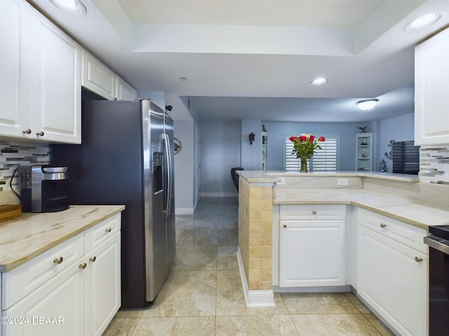 kitchen with white cabinetry, a raised ceiling, decorative backsplash, and kitchen peninsula