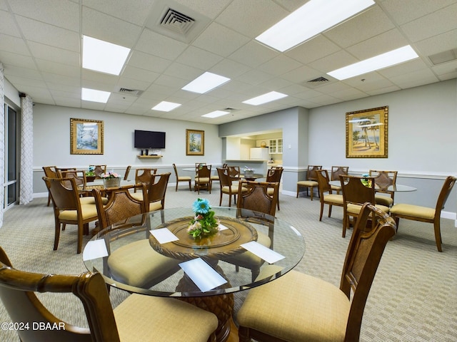 carpeted dining room featuring a paneled ceiling