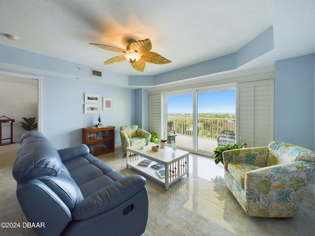 living room with ceiling fan and a textured ceiling