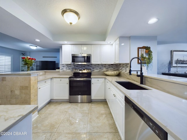 kitchen featuring white cabinetry, sink, light stone counters, appliances with stainless steel finishes, and backsplash