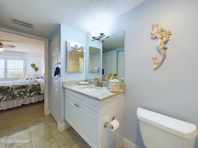 bathroom featuring ceiling fan, a textured ceiling, vanity, tile patterned floors, and toilet