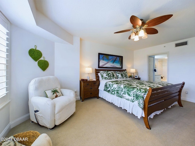 bedroom with connected bathroom, light colored carpet, and ceiling fan