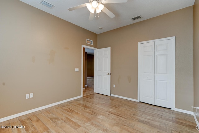 unfurnished bedroom featuring ceiling fan, a closet, and light wood-type flooring