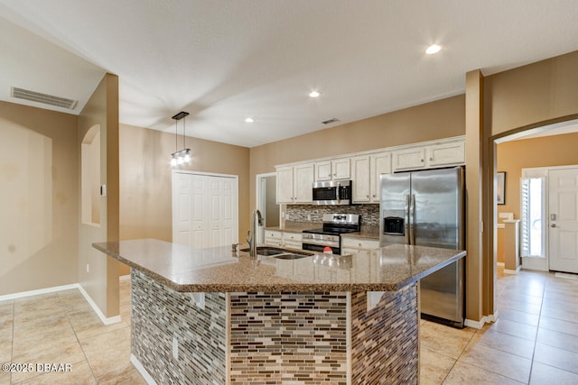 kitchen with a breakfast bar, white cabinetry, hanging light fixtures, stainless steel appliances, and a large island with sink