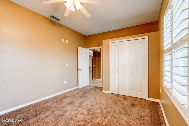 unfurnished bedroom featuring carpet flooring, ceiling fan, and a closet