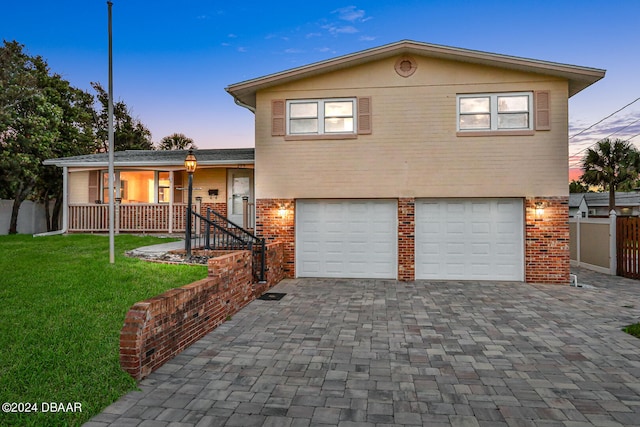 tri-level home with a garage and a lawn