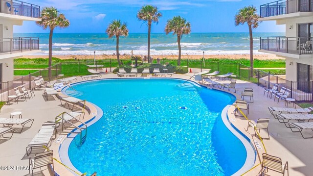 view of pool with a beach view, a water view, and a patio area