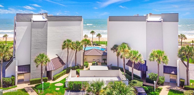 view of building exterior with a beach view and a water view