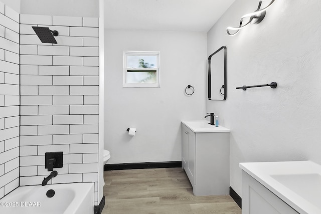 full bathroom featuring tiled shower / bath, hardwood / wood-style floors, vanity, and toilet