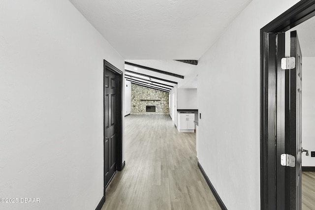 corridor with vaulted ceiling with beams and light hardwood / wood-style flooring