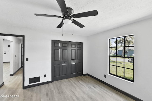 unfurnished bedroom featuring multiple windows, a closet, ceiling fan, and light hardwood / wood-style floors