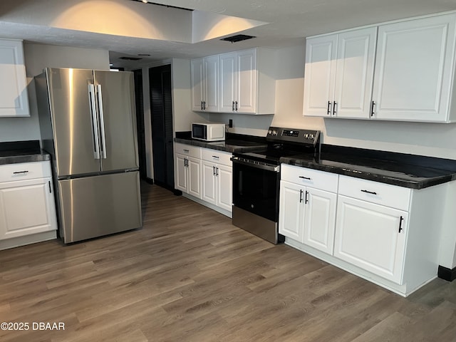 kitchen with appliances with stainless steel finishes, dark hardwood / wood-style floors, and white cabinetry