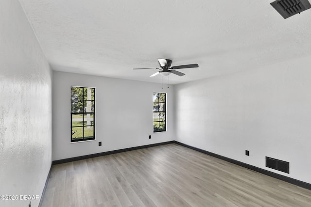 empty room featuring plenty of natural light, light hardwood / wood-style floors, a textured ceiling, and ceiling fan