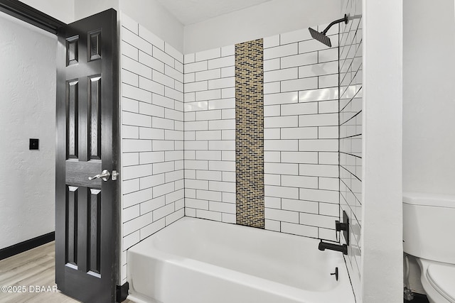 bathroom featuring hardwood / wood-style flooring, toilet, and tiled shower / bath