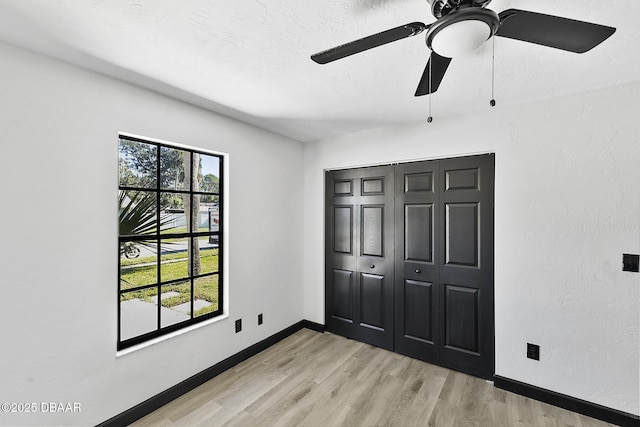 unfurnished bedroom with light hardwood / wood-style flooring, a closet, and ceiling fan