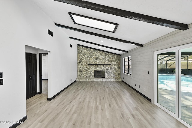 unfurnished living room featuring a fireplace, vaulted ceiling with beams, and light hardwood / wood-style flooring