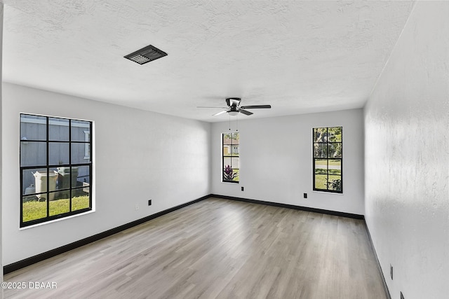 spare room featuring ceiling fan, light hardwood / wood-style flooring, and a textured ceiling