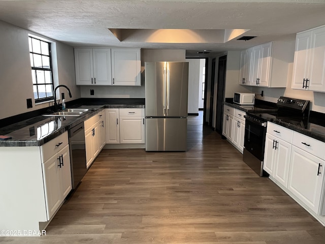 kitchen with a tray ceiling, sink, black appliances, hardwood / wood-style flooring, and white cabinets