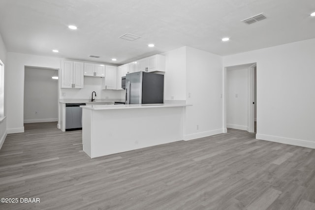 1324 Powers Ave, Holly Hill, FL 32117 - kitchen with stainless steel appliances, white cabinetry, light countertops, light wood-style floors, and a peninsula